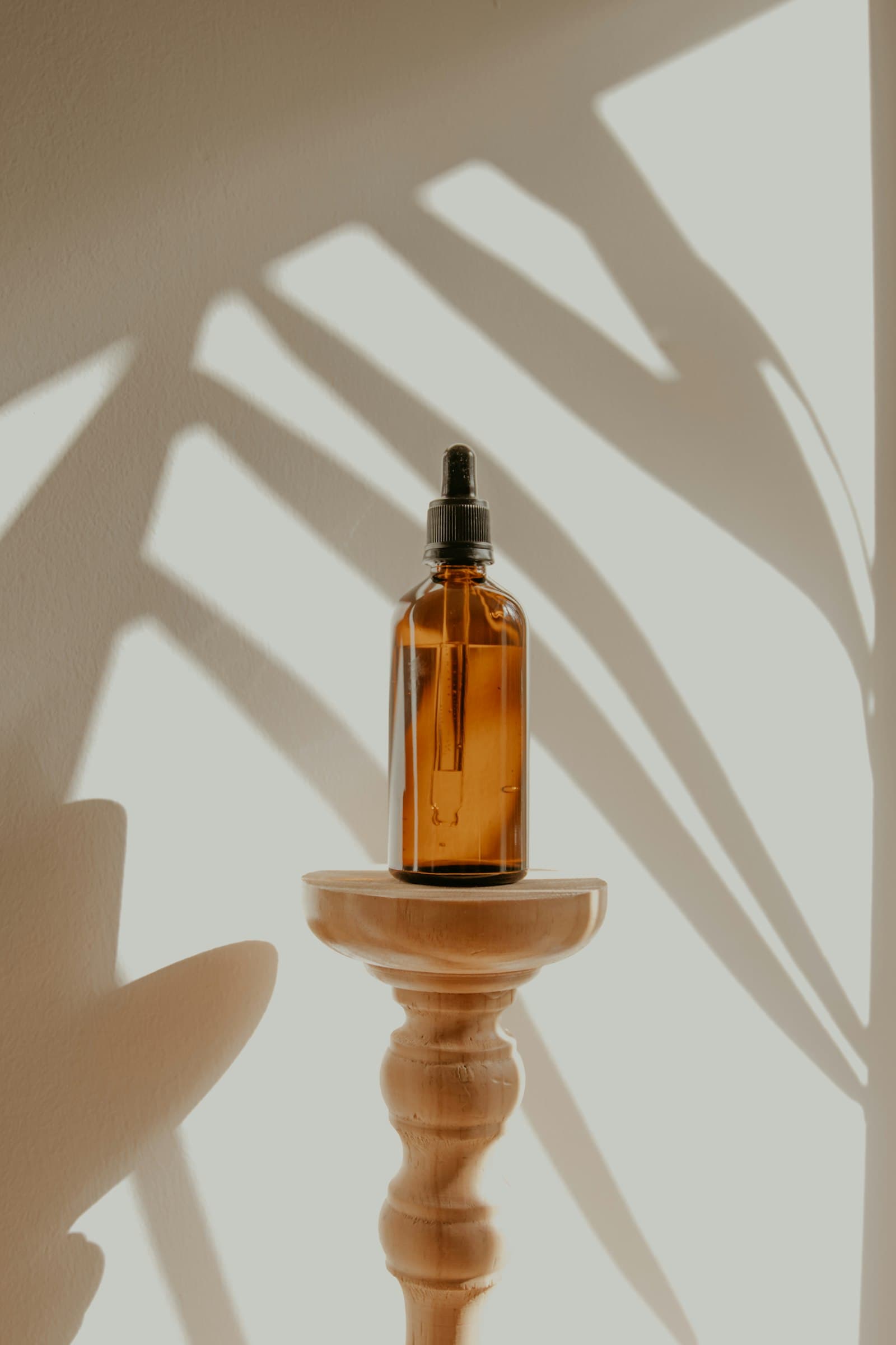 Treatment oils on a shelf, palm shadow across the wall